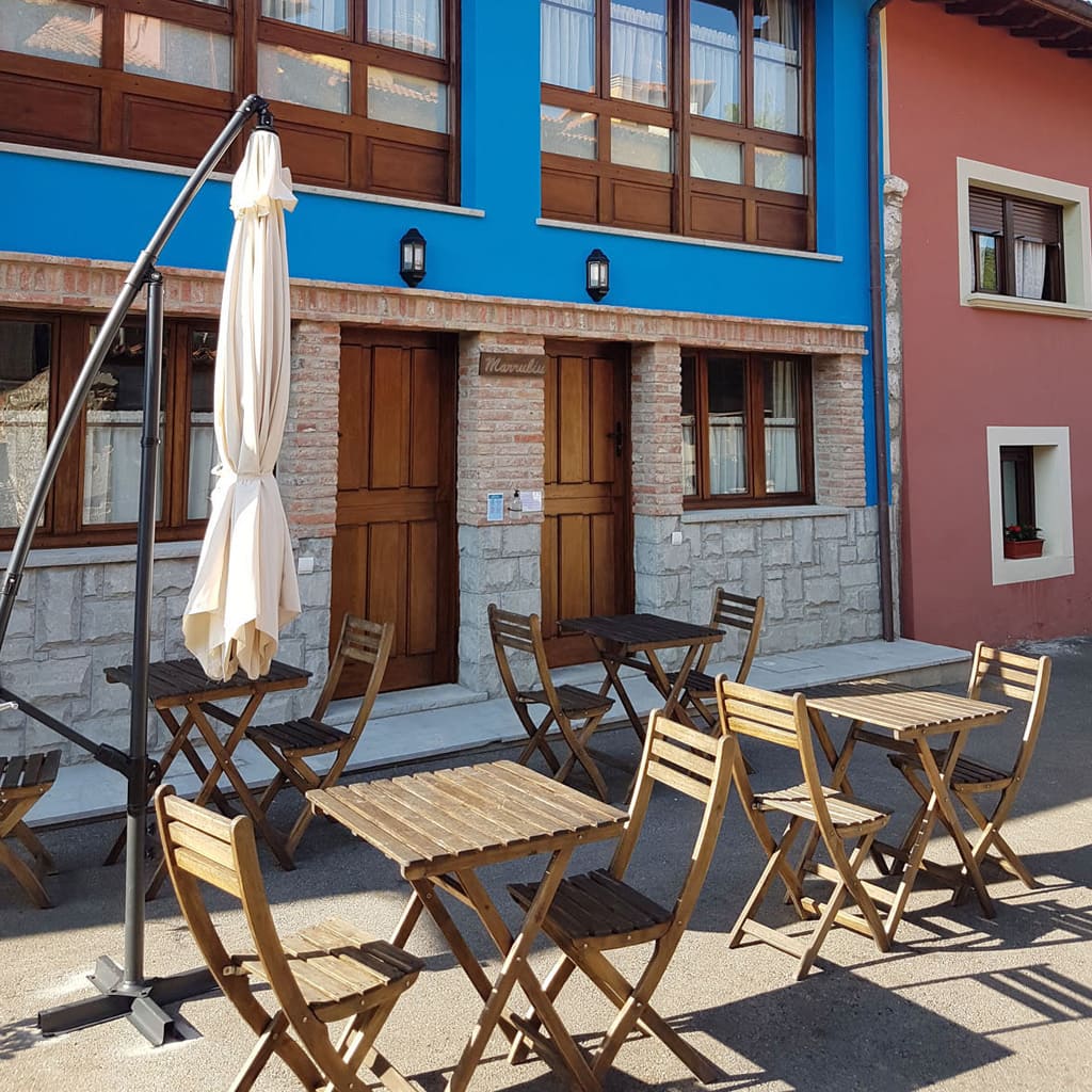 Terraza exterior de los Apartamentos Marrubiu con mesas y sillas de madera.